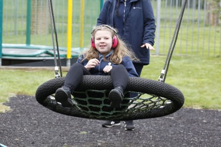 young person enjoys swinging on tyre swing