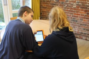 Young person and Autism Practitioner looking at Prior Insight on tablet